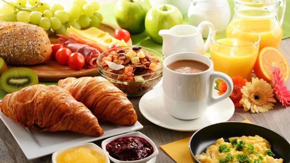 Mesa de desayuno empresarial con panadería, frutas, jugo y café en Bogotá